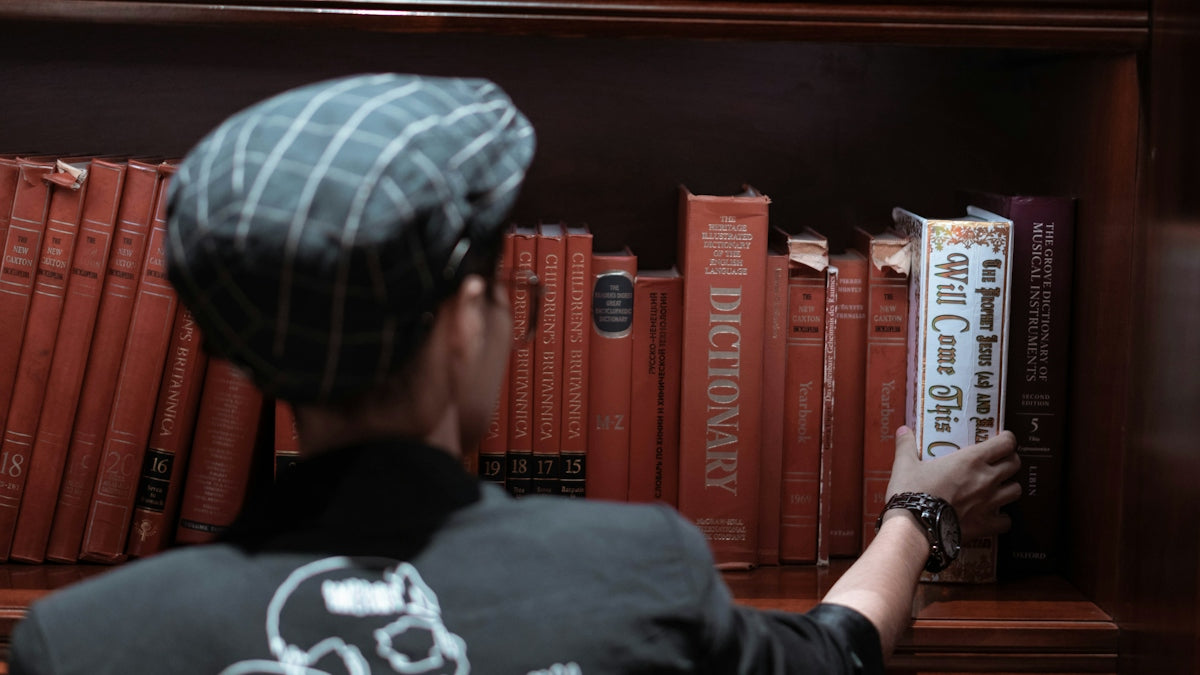 Person reaching for a book on matching sets in a library, focusing on women's matching sets men's fashion coordination.