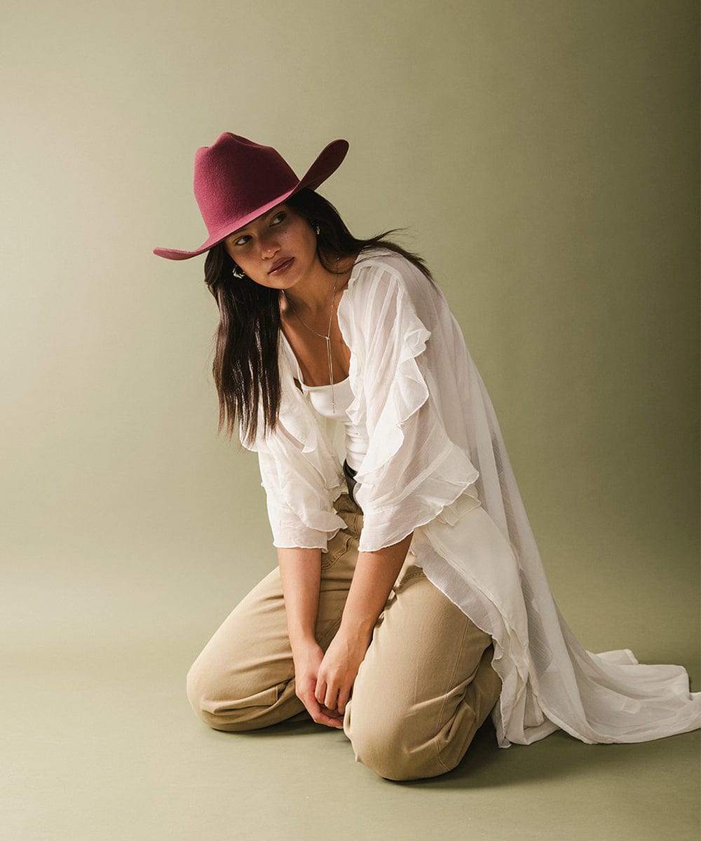 Model showcasing the latest fashion arrivals with a burgundy hat and white flowing outfit.