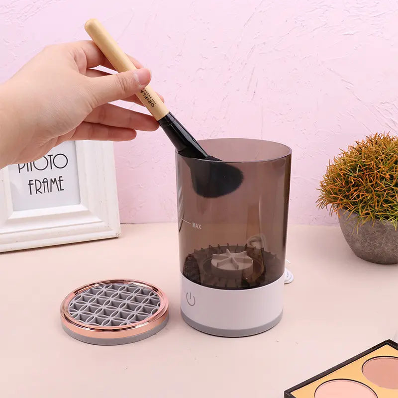 Person using a rechargeable makeup brush cleaner to wash a makeup brush in a convenient device.