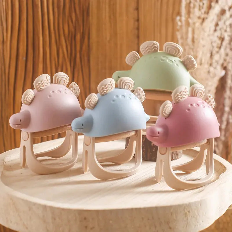 Silicone dinosaur teether and rattle toy for babies, 0-12 months, featuring colorful dinosaur design and textured surface for chewing.