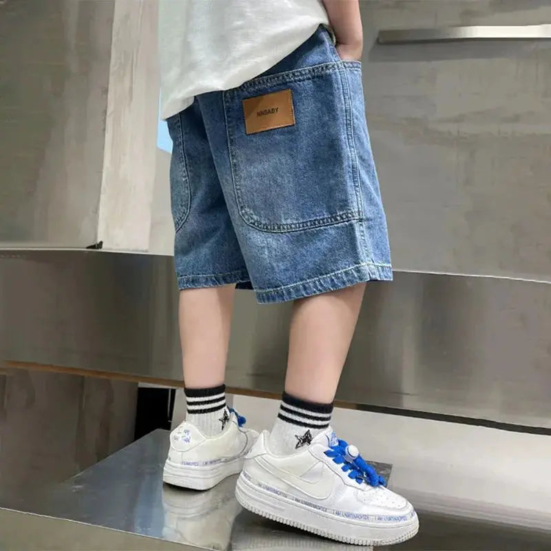 Boy wearing denim shorts from SHOPEZRA L.L.C., knee-length casual summer trousers for kids age 3-12, outdoor five-point style.