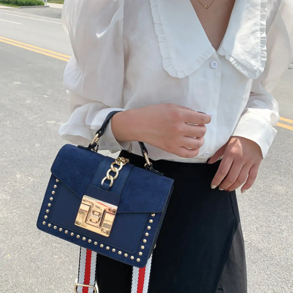 Stylish woman holding a Fiona shoulder bag, featuring vegan leather shoulder bag with gold studs and chain detail.