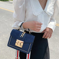 Stylish woman holding a Fiona shoulder bag, featuring vegan leather shoulder bag with gold studs and chain detail.