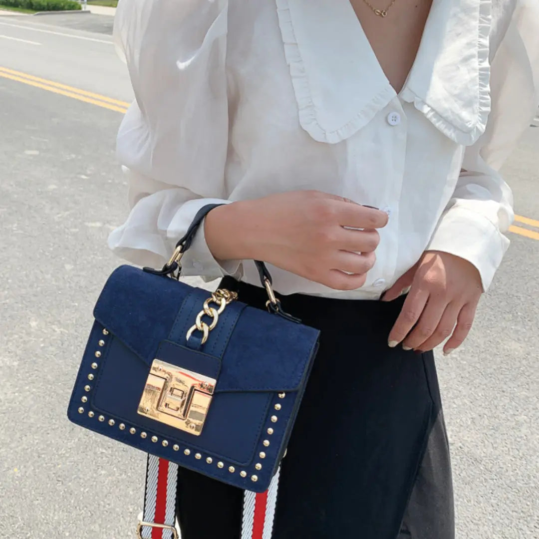 Stylish woman holding a Fiona shoulder bag, featuring vegan leather shoulder bag with gold studs and chain detail.