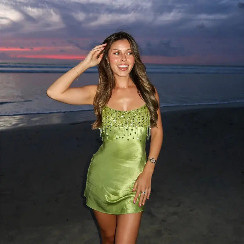 Green satin dress with sequin tassels, low neckline, spaghetti straps, back zipper, suitable for beach parties and elegant occasions.