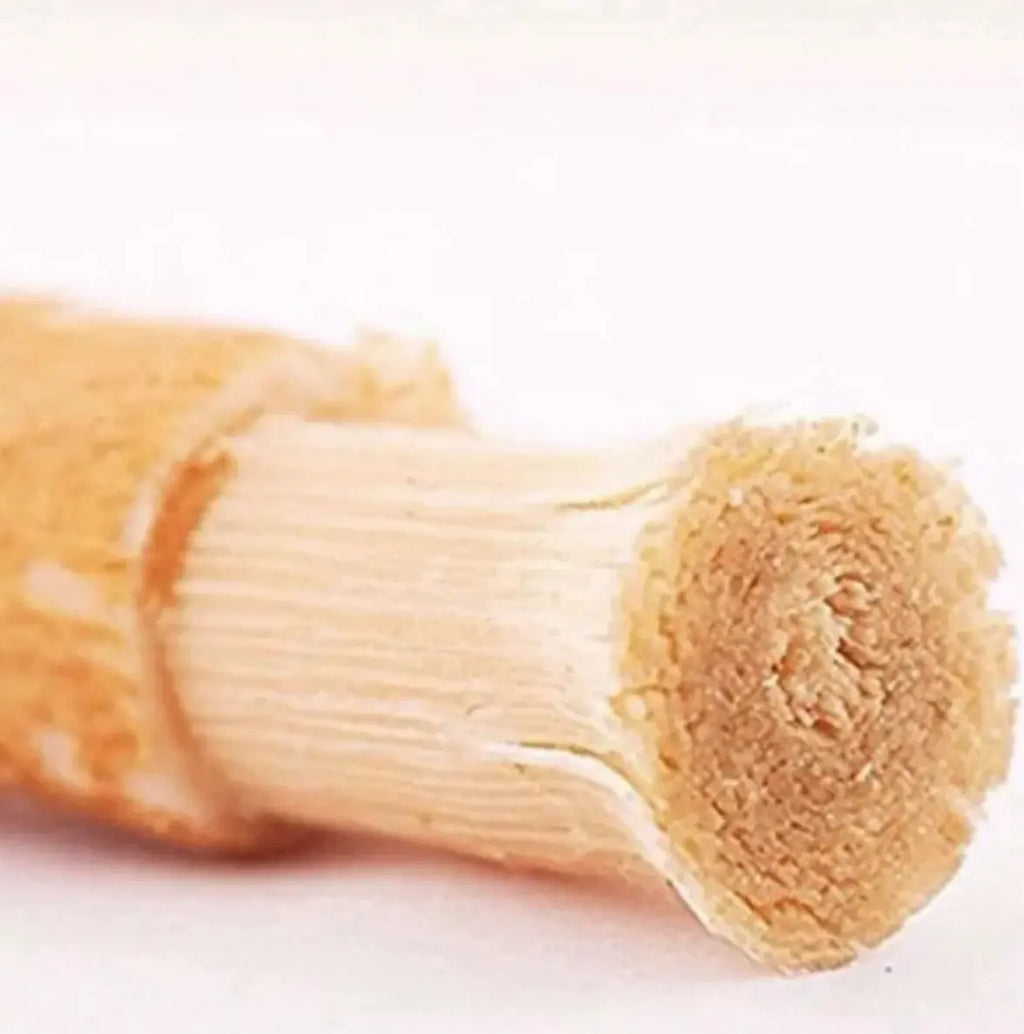 Close-up view of a natural miswak tooth cleaning stick, showcasing its thin wood texture and brushing end.
