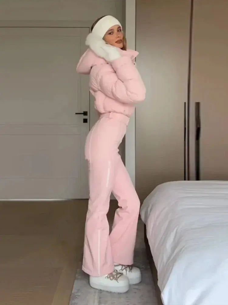 Pink women’s ski jumpsuit with fur collar, hood, high waist, and zipper closure, suitable for winter outdoor wear.