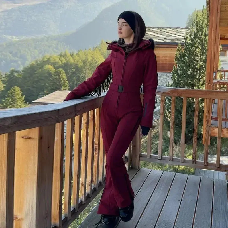 Pink women's fur collar hooded skiwear jumpsuit with high waist, zipper closure, slim fit, suitable for winter outdoor activities.