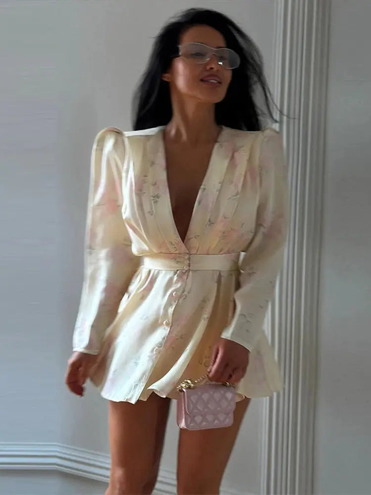 Pink printed casual mini dress for women with full sleeves, V-neck, button details, and waist tape, suitable for spring summer beach wear.