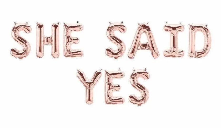 Rose gold balloon banner decor spelling 'SHE SAID YES' for bridal showers and celebrations.